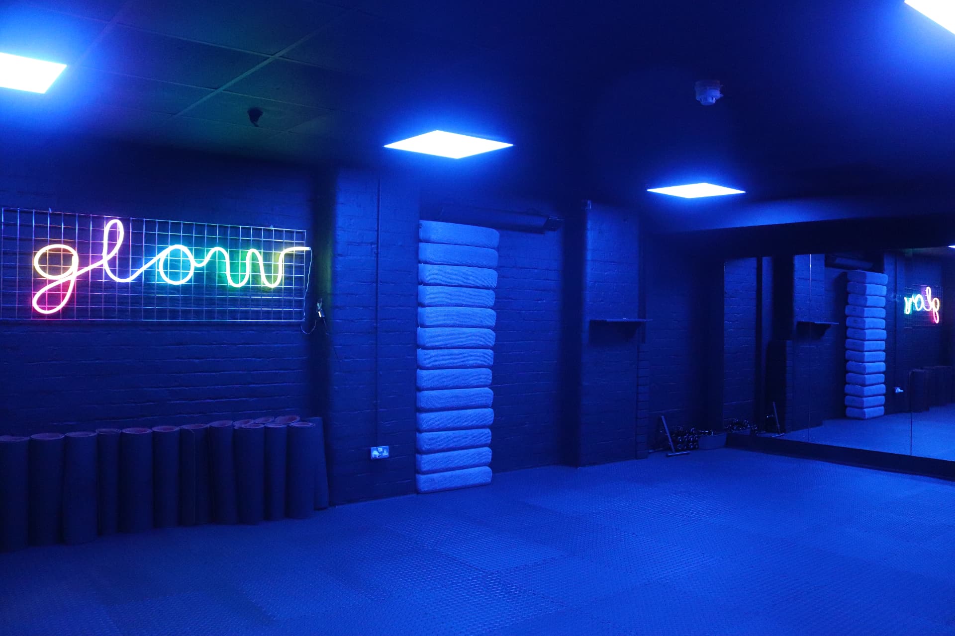 Glow Studio under cool blue lighting with mirrors and exercise mats